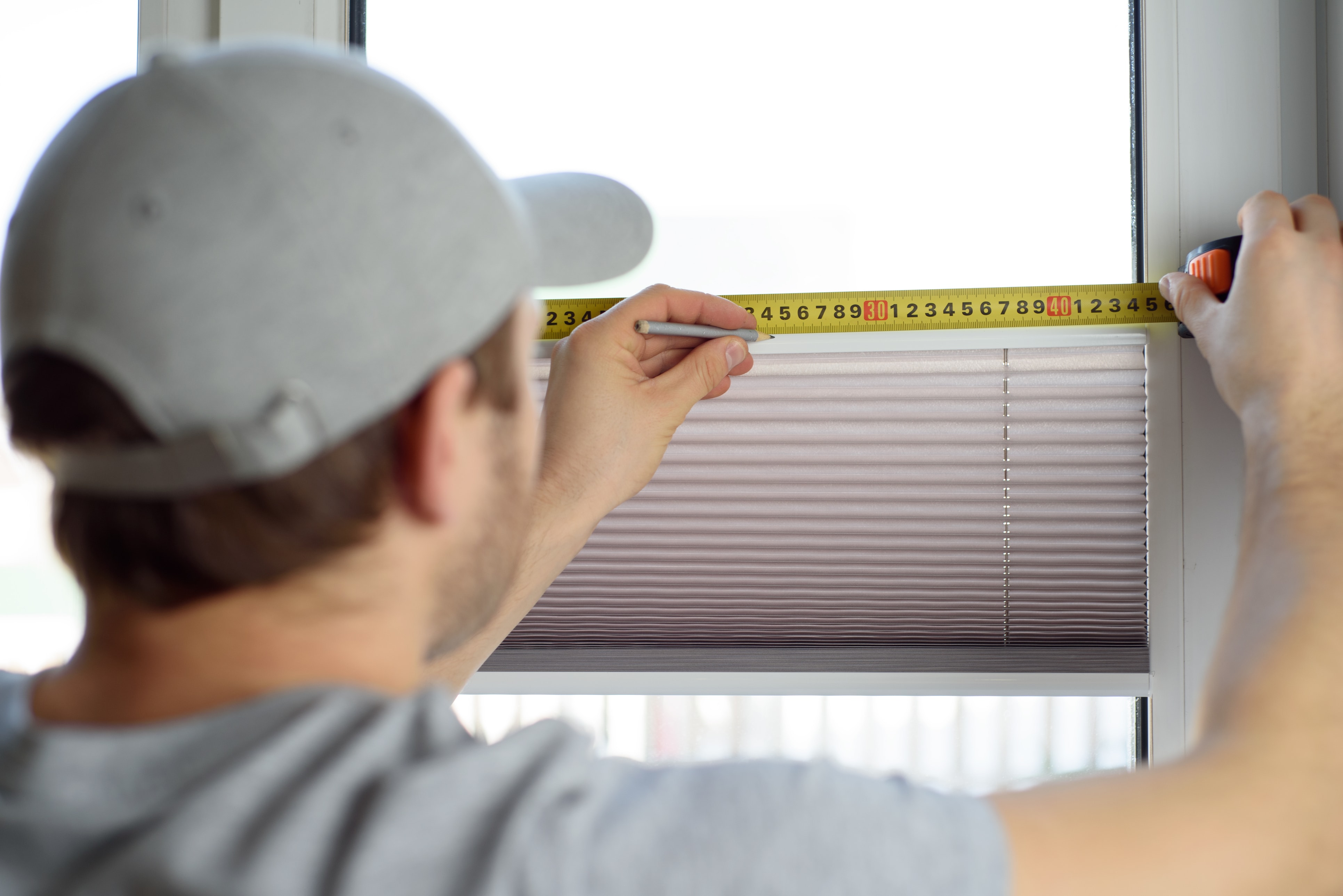 Man installing gray pleated blinds on the window